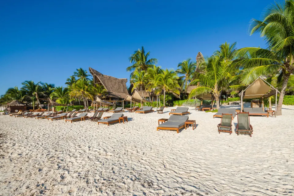 Wide beach scene with rows of loungers and blue sky at Ahau Tulum