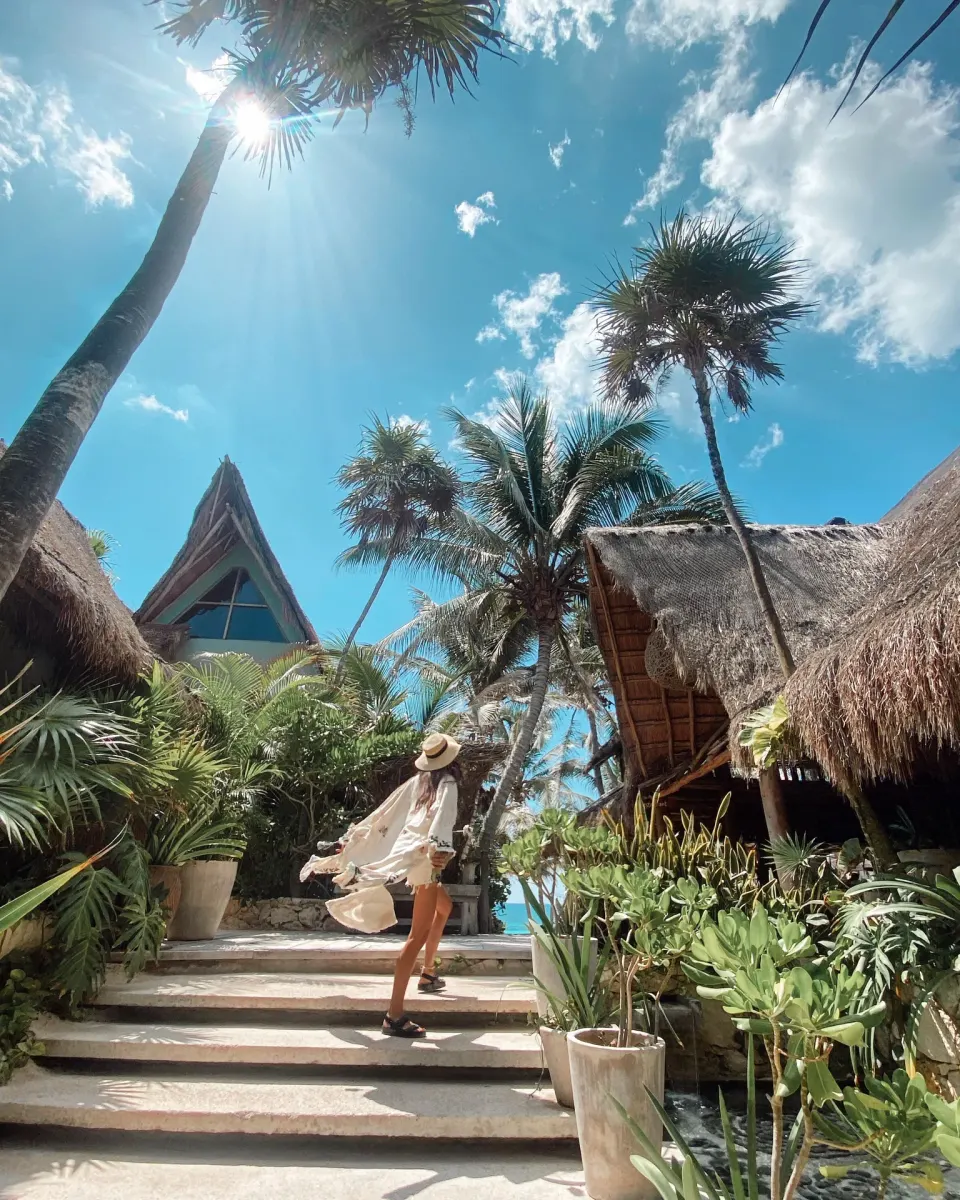 Guest walking up tropical steps through thatched pathways at Ahau Tulum