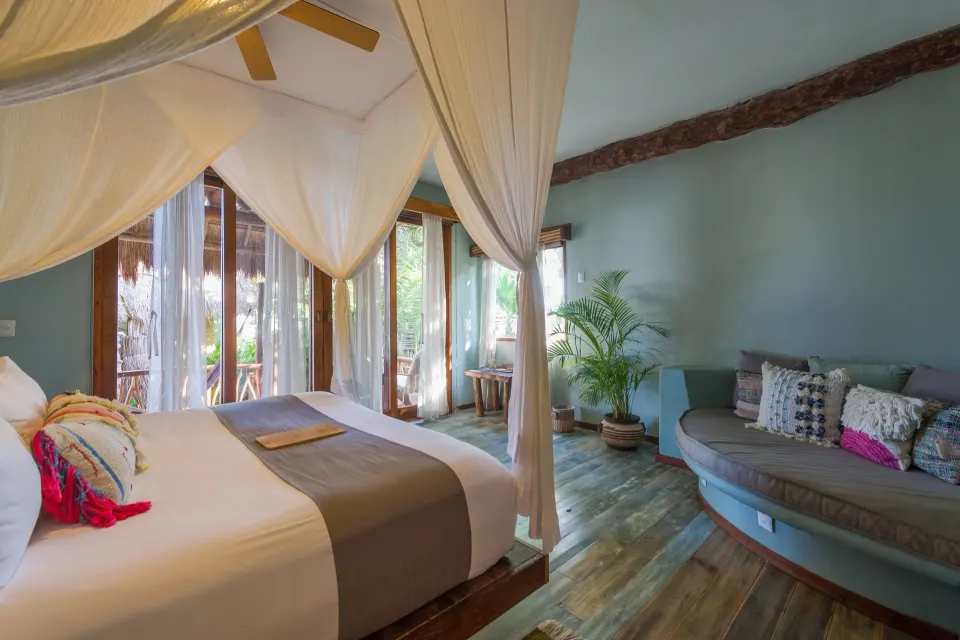 Spacious canopy bedroom with sofa seating and terrace doors at Ahau Tulum