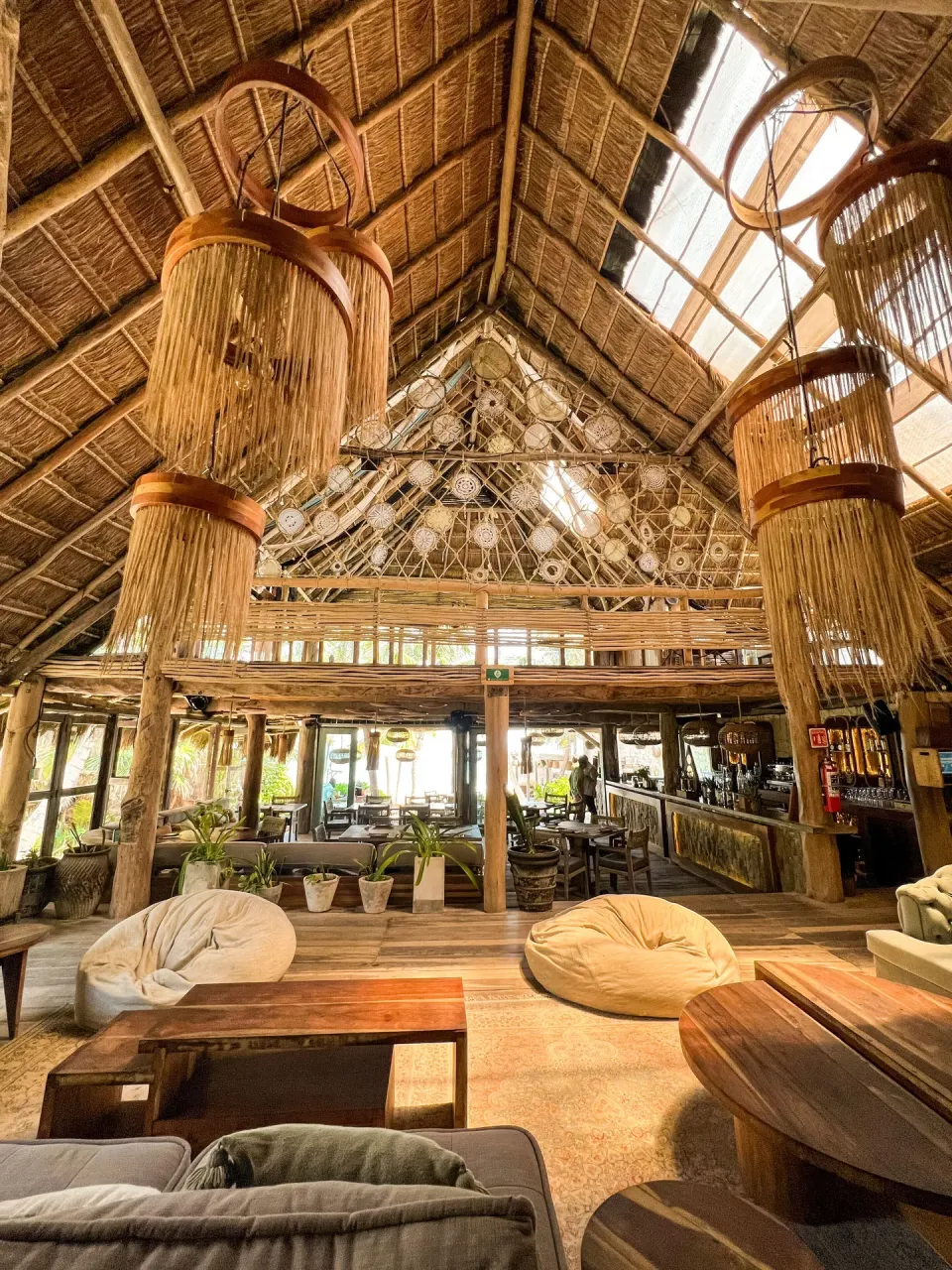 Spacious thatched-roof lobby with hanging fringed lamps at Ahau Tulum