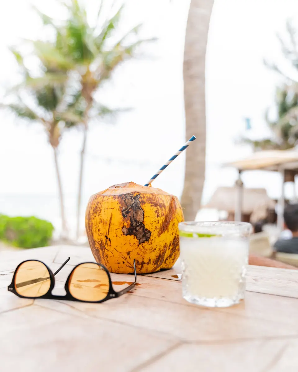 Fresh coconut and cocktail on a beach table at Ahau Tulum
