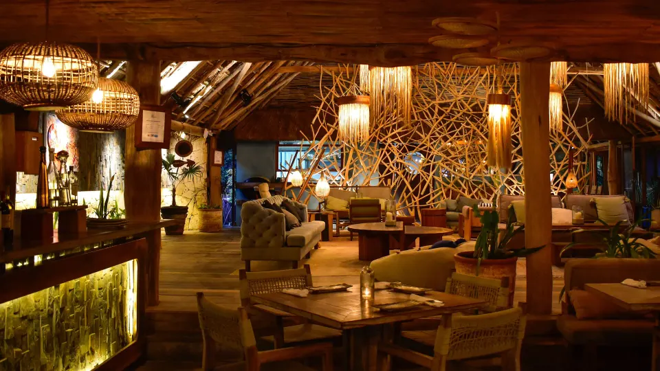 Warmly lit interior dining room with woven light fixtures at Ahau Tulum.