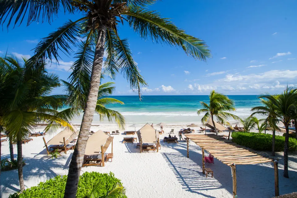 Wooden table set with breakfast plates and juice overlooking the beach at Ahau Tulum