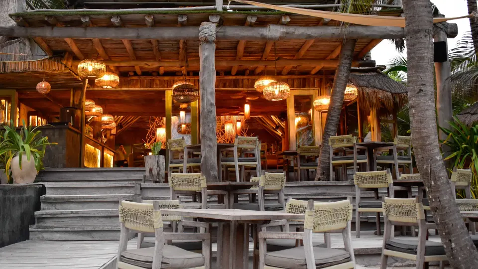 Oceanfront dining terrace with tables and wicker chairs at Ahau Tulum.