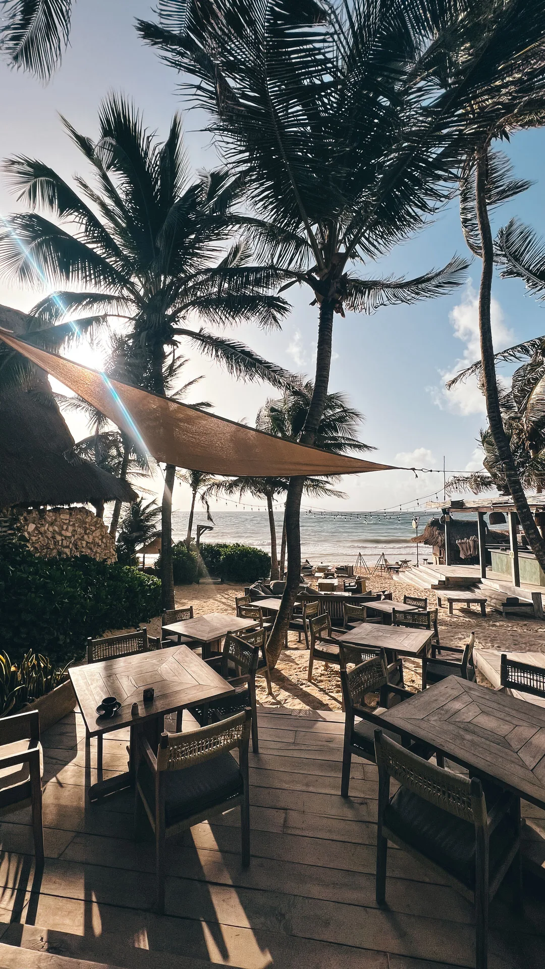 Outdoor beachfront dining tables and chairs under shade sails at Ahau Tulum