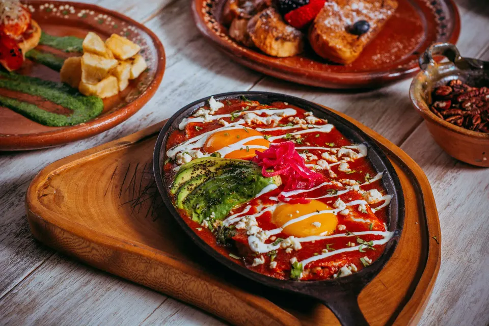 Cast-iron skillet of shakshuka with avocado and eggs at Ahau Tulum