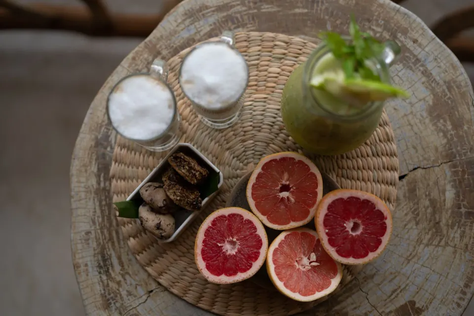 Top-down view of fresh grapefruit, cookies and two foamy drinks at Ahau Tulum