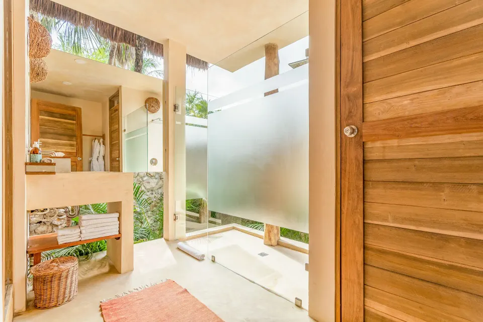 Open-plan bathroom area with sink and frosted glass shower in a Deluxe Room at Ahau Tulum