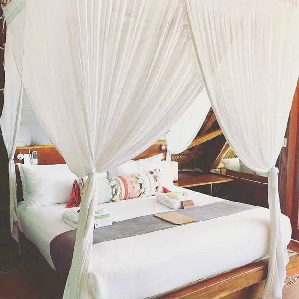 Close-up of canopy king bed with decorative cushions in Junior Suite at Ahau Tulum