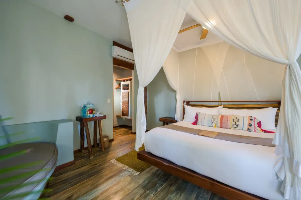 King canopy bed with bedside tables and green wall in Junior Suite at Ahau Tulum