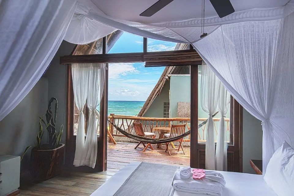 Spacious vaulted junior suite with canopy bed and balcony at Ahau Tulum