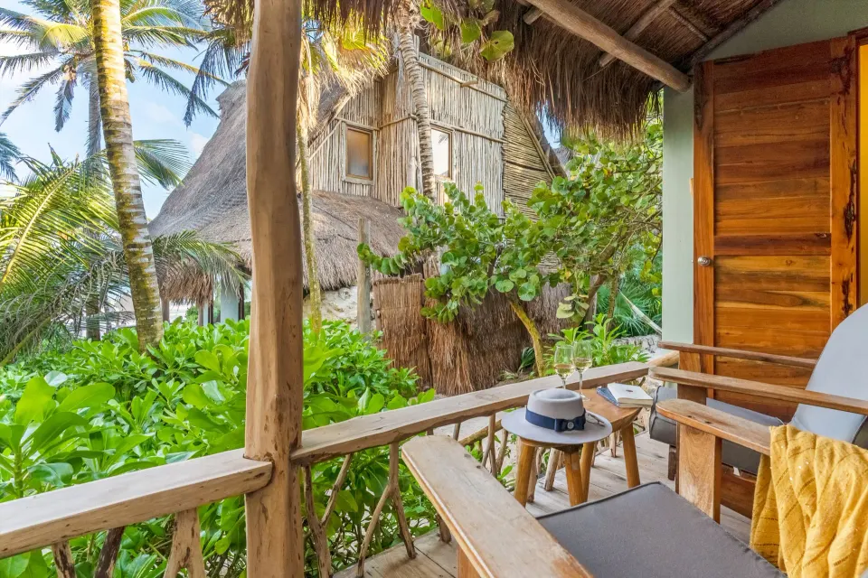 Beach-level balcony with wooden chairs and lush greenery at Ahau Tulum