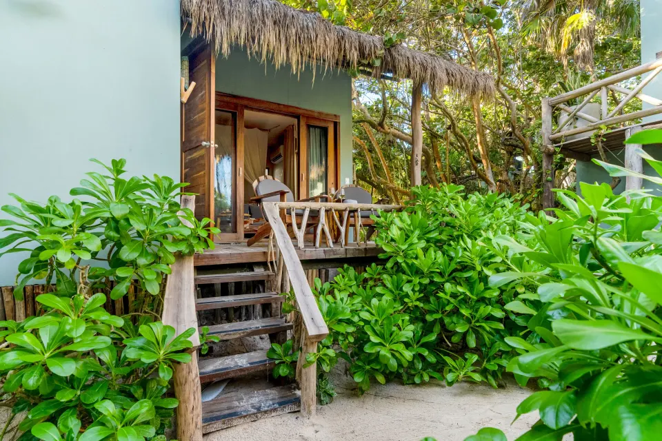 Exterior steps leading up to a beachfront junior suite terrace surrounded by greenery at Ahau Tulum