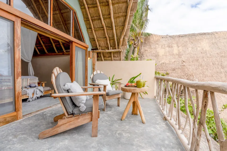 Balcony chairs and table on terrace with ocean glimpses at Ahau Tulum