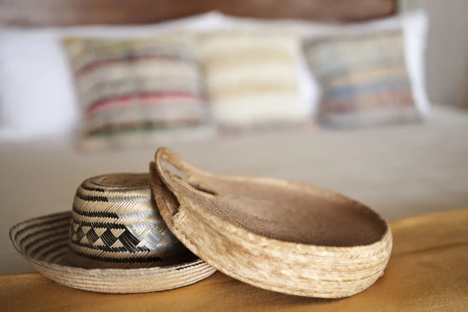 Woven hats and straw tray on a wooden surface in the Junior Suite at Ahau Tulum