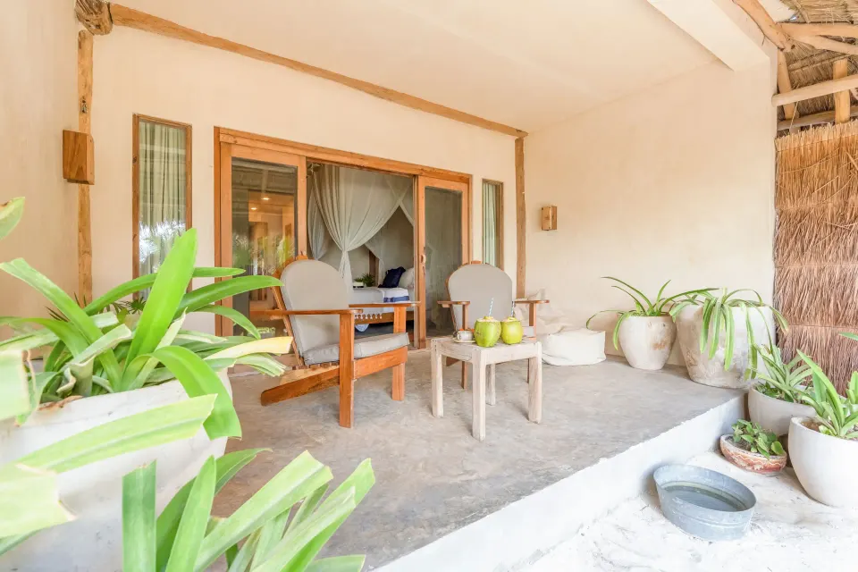 Shaded patio of a Junior Suite Oceanfront Beach level at Ahau Tulum with two armchairs and potted plants