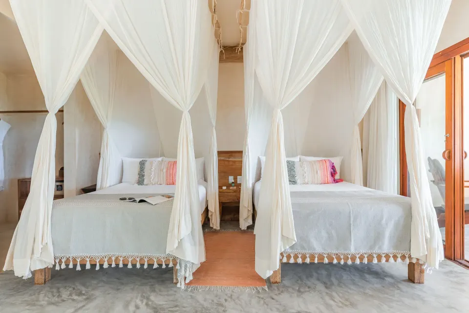Front-on shot of two canopy twin beds in a Junior Suite at Ahau Tulum.