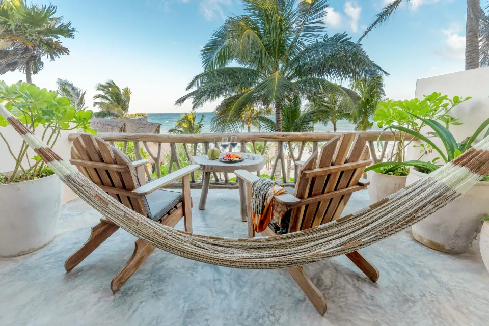 Hammock-framed balcony view with two chairs and ocean beyond at Ahau Tulum