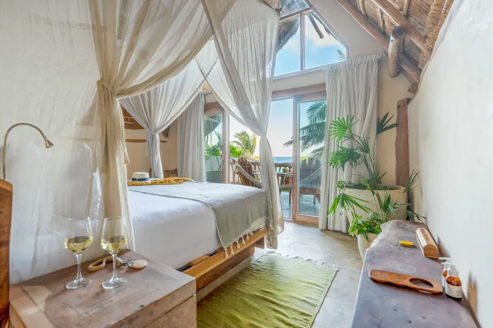 King bed with canopy and balcony view of palms and ocean in a Junior Suite at Ahau Tulum