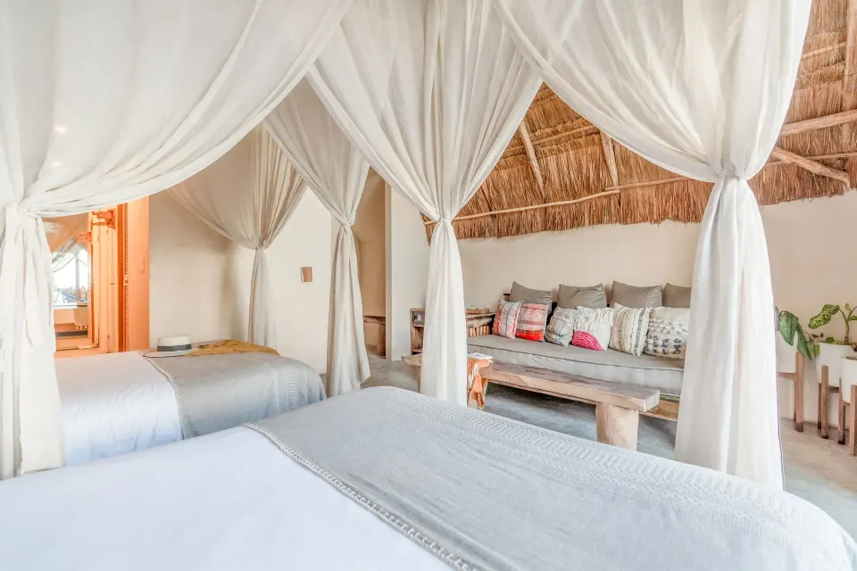 Twin canopy beds and sofa bench in the Junior Suite Oceanfront Top Level at Ahau Tulum