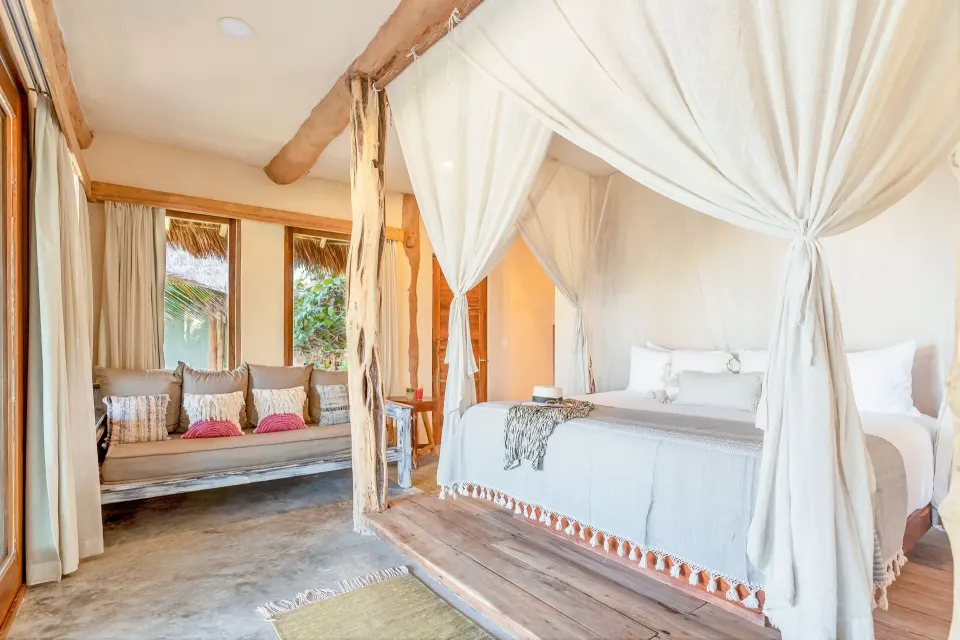 Canopied king bed with built-in daybed and natural wood accents in the Master Suite Oceanfront Beach Level at Ahau Tulum