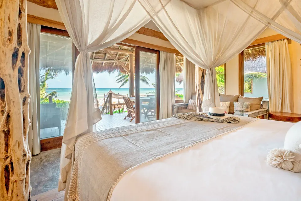 Canopied king bed and sliding glass doors opening to the terrace at the Master Suite Oceanfront Beach Level, Ahau Tulum