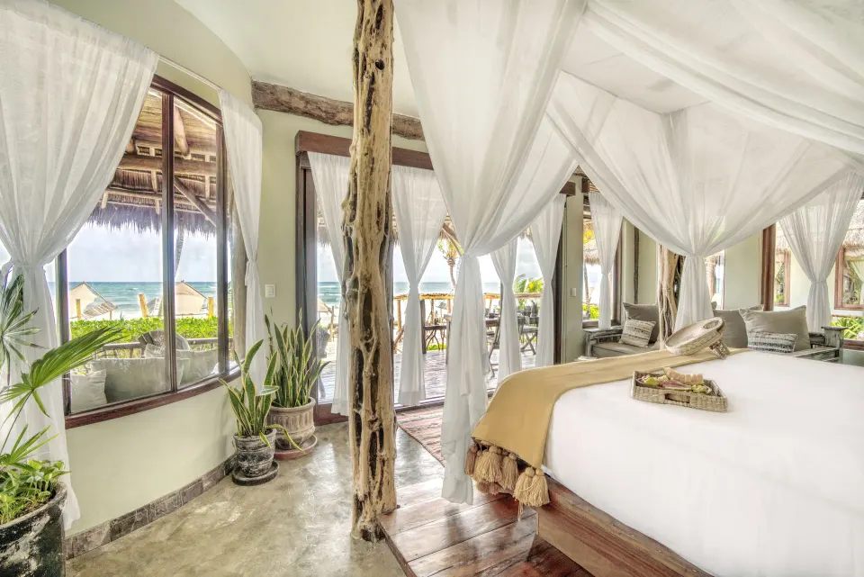 Bright bedroom with king bed, multiple windows and ocean glimpses in the Master Suite Oceanfront Beach Level at Ahau Tulum