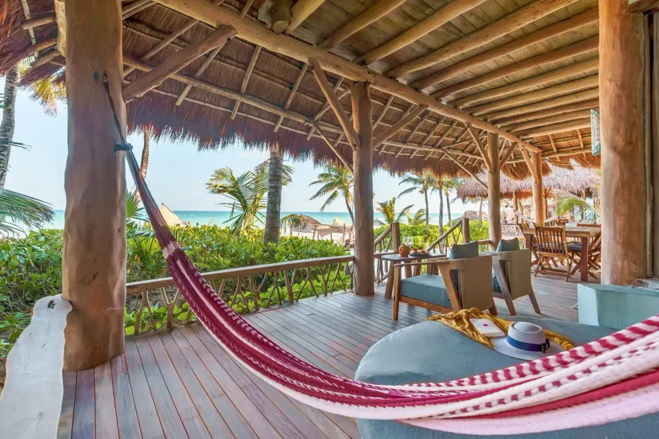 Hammock and wooden terrace of the Master Suite Oceanfront Beach Level at Ahau Tulum, with palm trees and ocean beyond