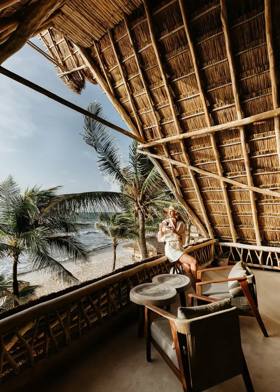 Guest on the Master Suite balcony with palm-lined beach and ocean at Ahau Tulum