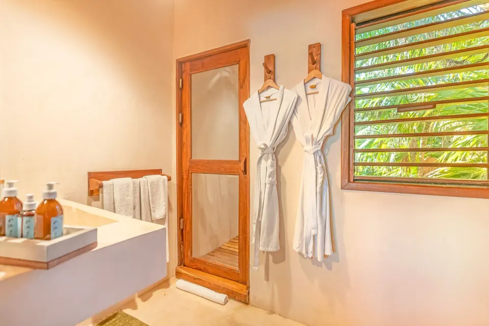 Bathroom with hanging robes and louvered window in the Master Suite Oceanfront at Ahau Tulum