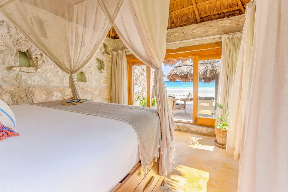 Canopy king bed and open doors to the beach at Ahau Tulum
