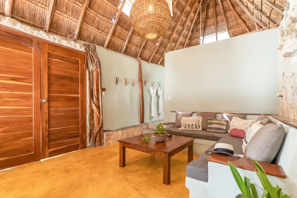 Living area with sofa and coffee table under palapa roof at Ahau Tulum
