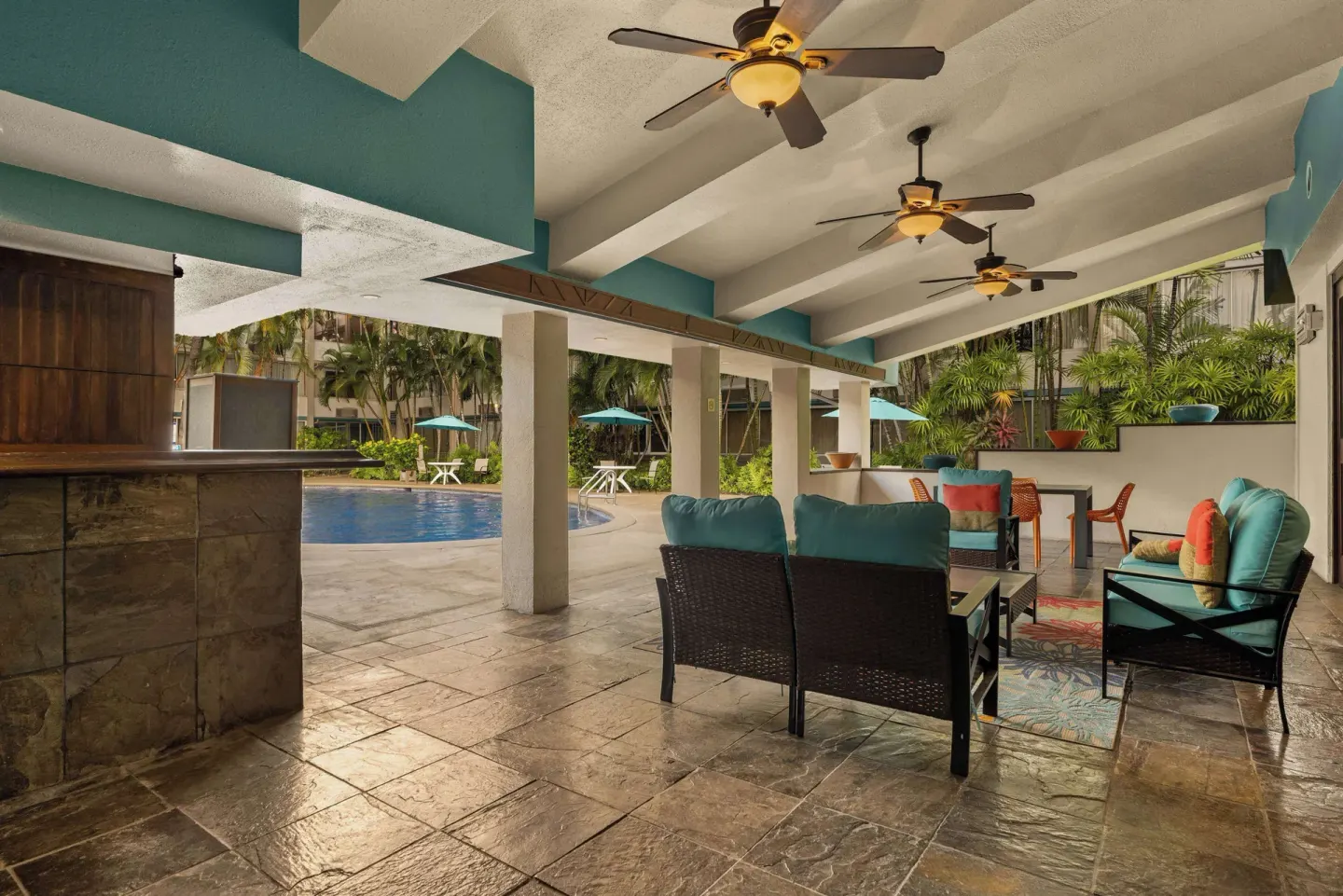 Covered poolside seating area with lounge furniture at Airport Honolulu Hotel.