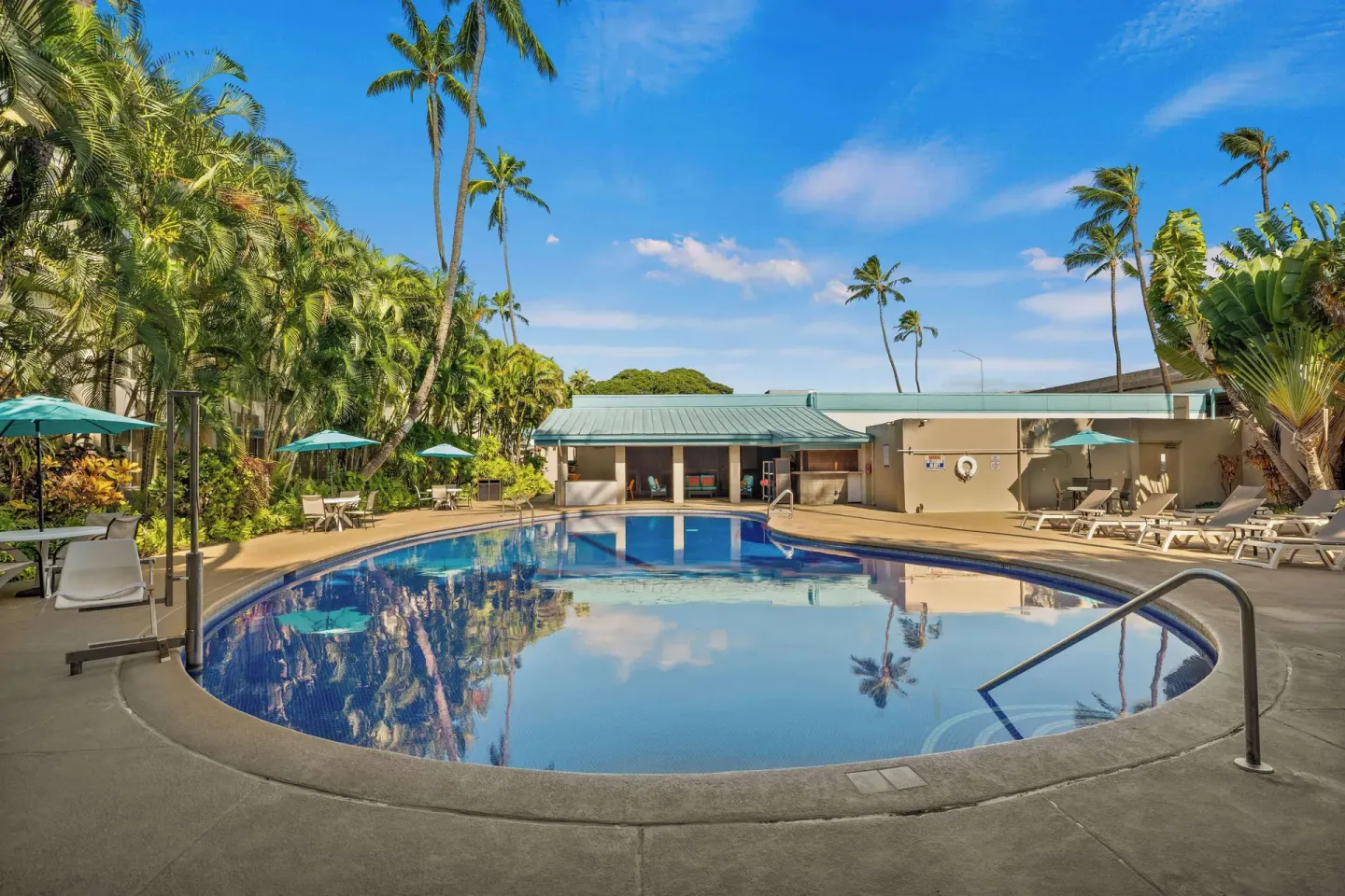 Curved outdoor pool surrounded by palms at Airport Honolulu Hotel.