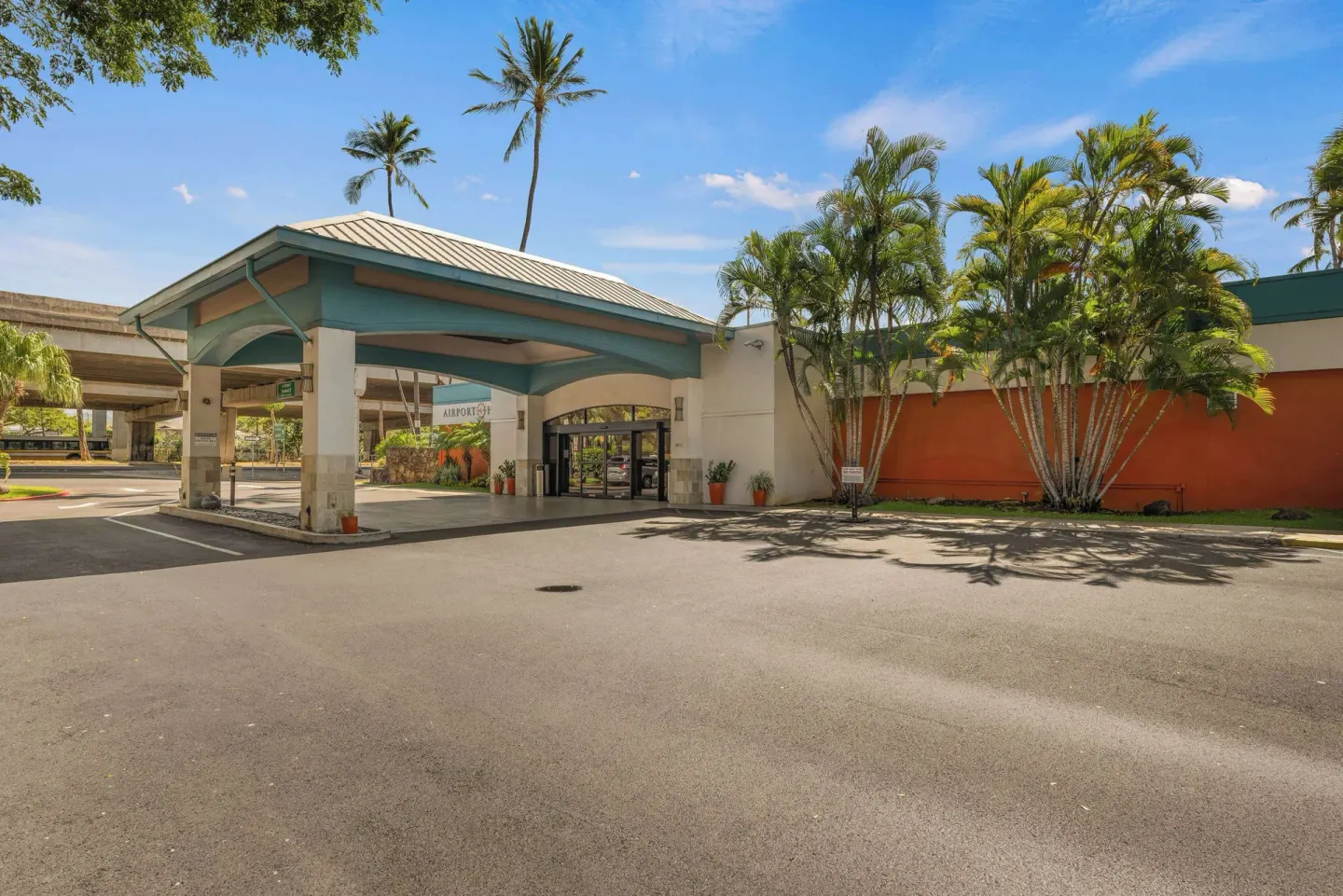 Wide view of the entrance canopy and palms at Airport Honolulu Hotel.