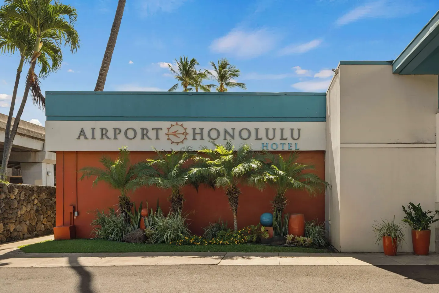 Airport Honolulu Hotel exterior sign with tropical landscaping and palm trees.