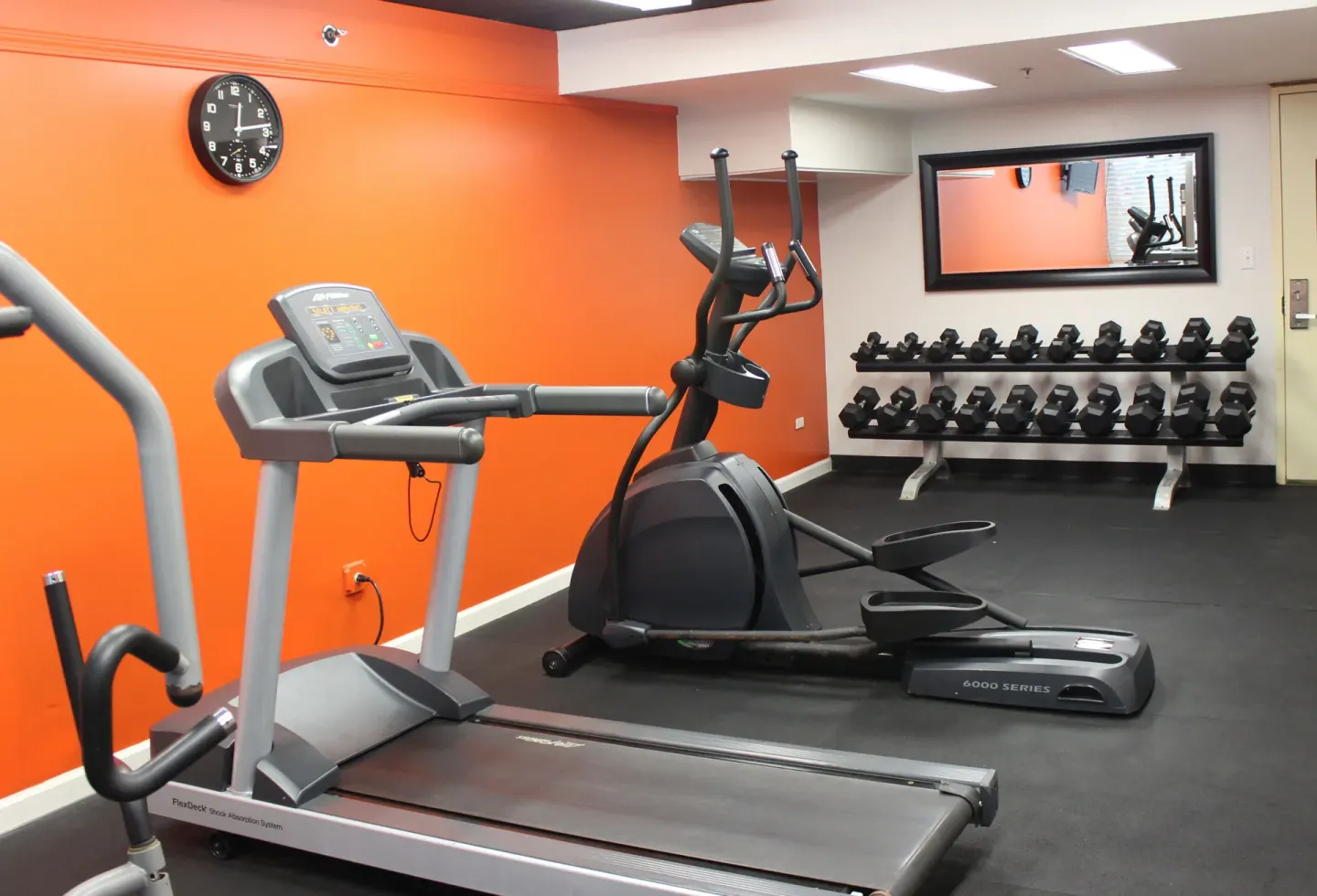 Fitness room with treadmill, elliptical, and dumbbells at Airport Honolulu Hotel.