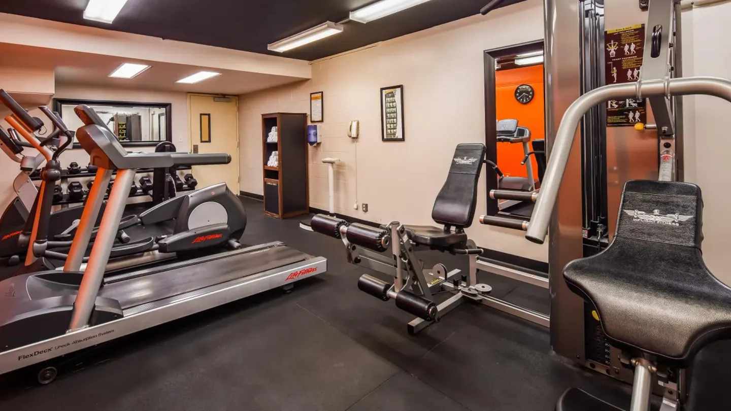 Fitness room at Airport Honolulu Hotel with treadmills, weights, and strength machines.