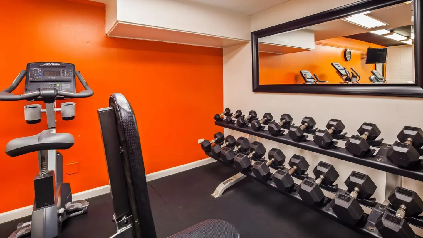 Fitness room with dumbbells and an exercise bike at Airport Honolulu Hotel.
