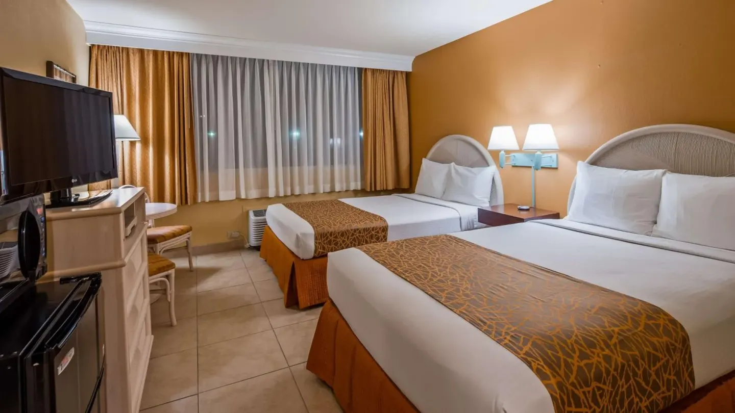Two-bed guest room with tile floor, TV and small table at Airport Honolulu Hotel.