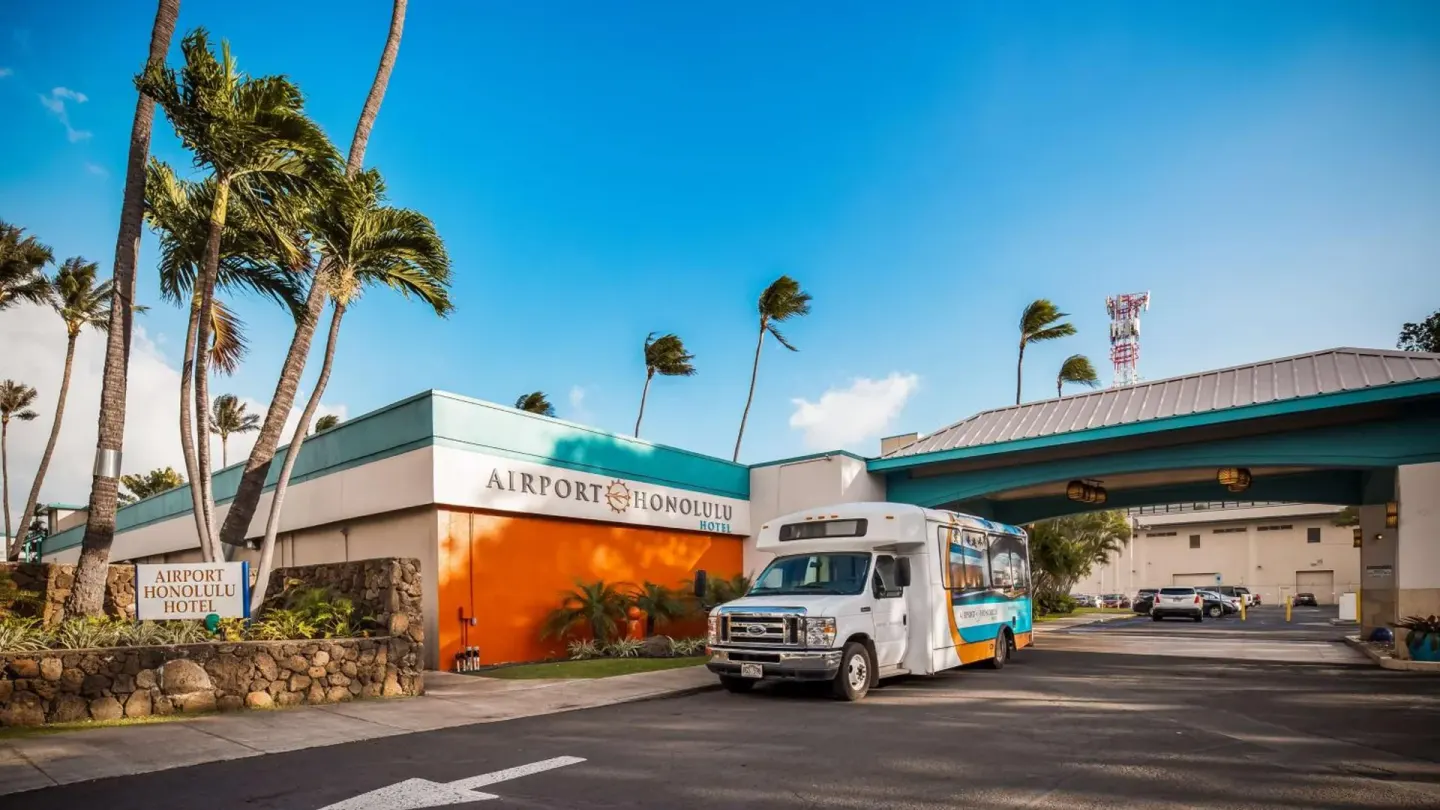 Airport Honolulu Hotel exterior with shuttle bus, palms and covered drive.