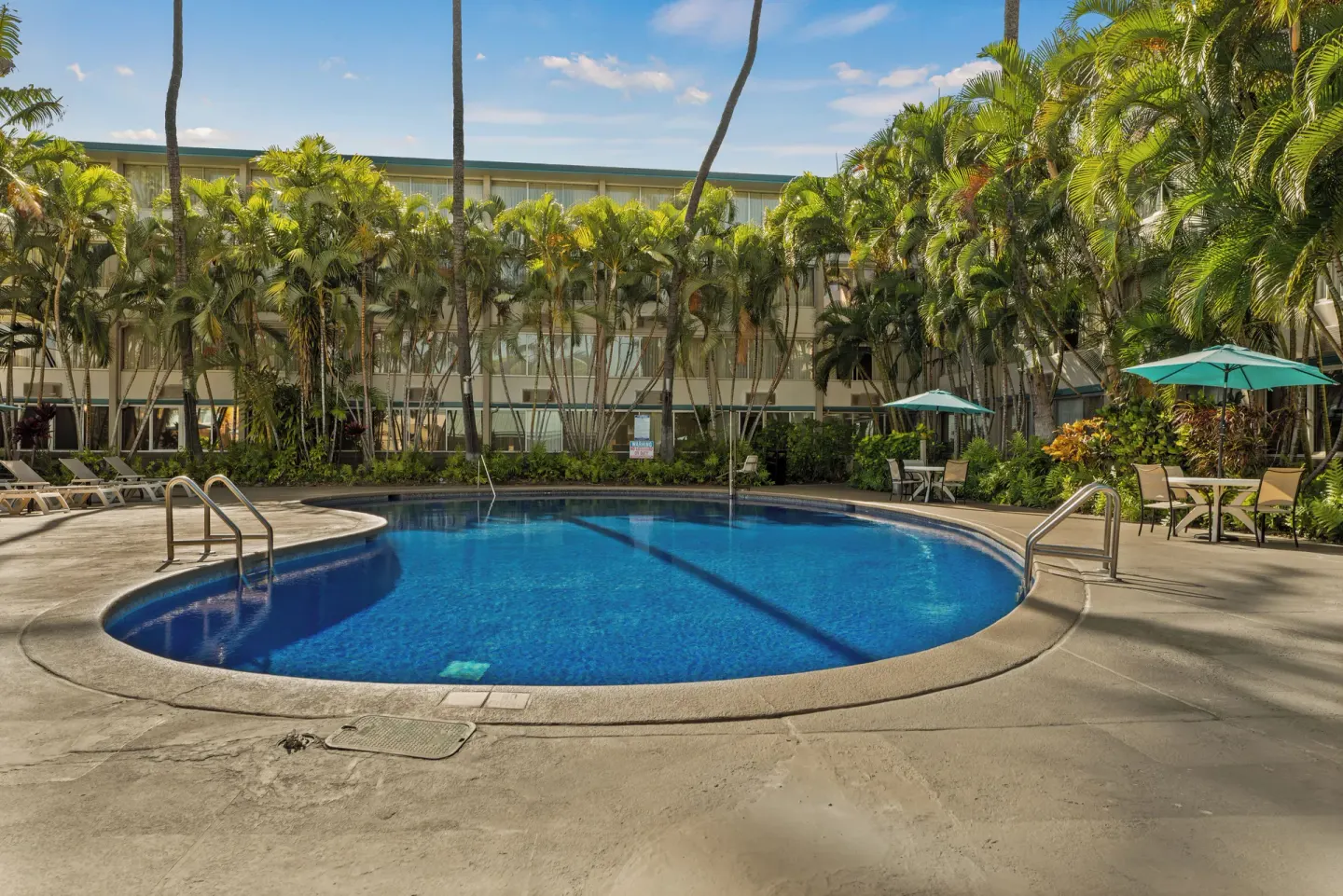 Outdoor pool with palm trees and patio seating at Airport Honolulu Hotel.