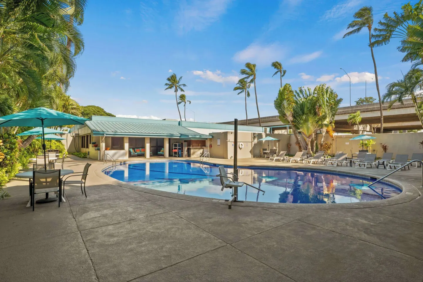 Pool deck with umbrellas, palms, and loungers at Airport Honolulu Hotel.