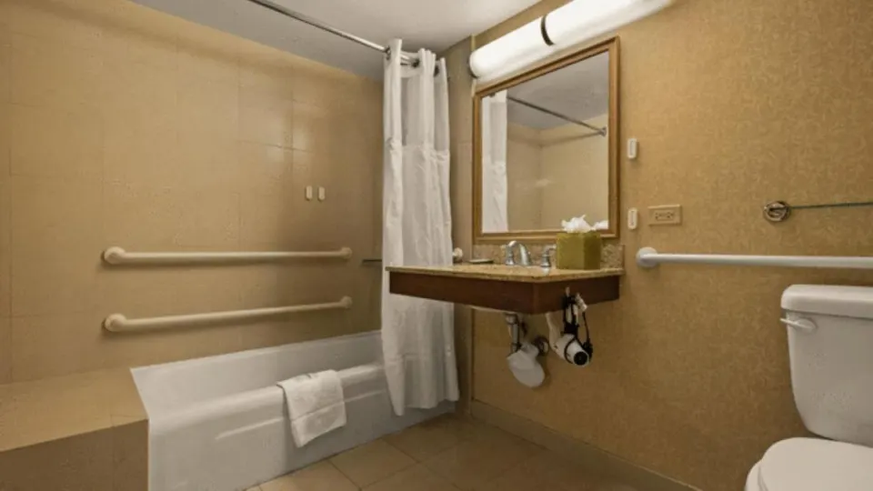 Accessible bathroom with tub, grab bars and vanity at Airport Honolulu Hotel.