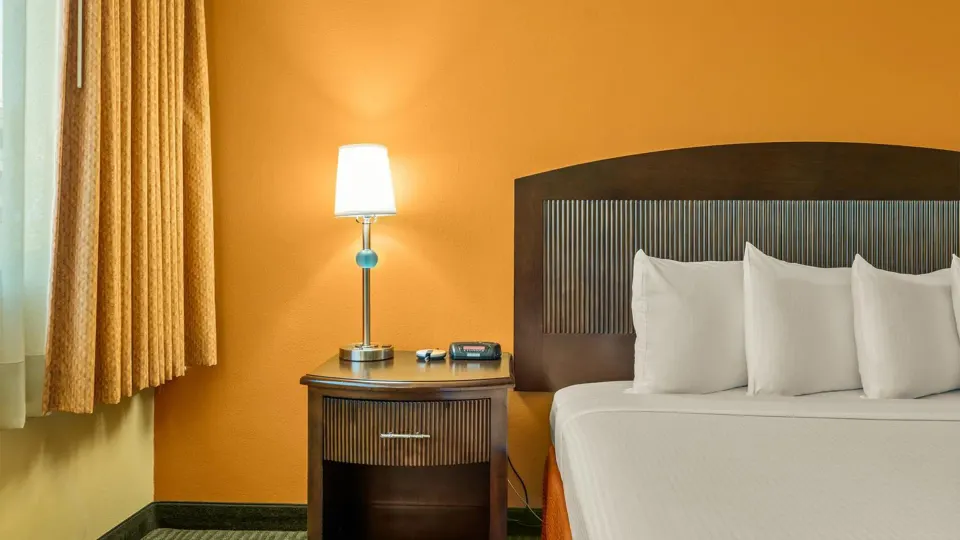 Non-smoking room bedside view with bed, nightstand and lamp at Airport Honolulu Hotel.