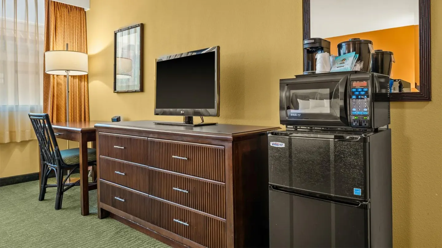 Non-smoking room dresser with TV, desk, microwave and mini-fridge at Airport Honolulu Hotel.