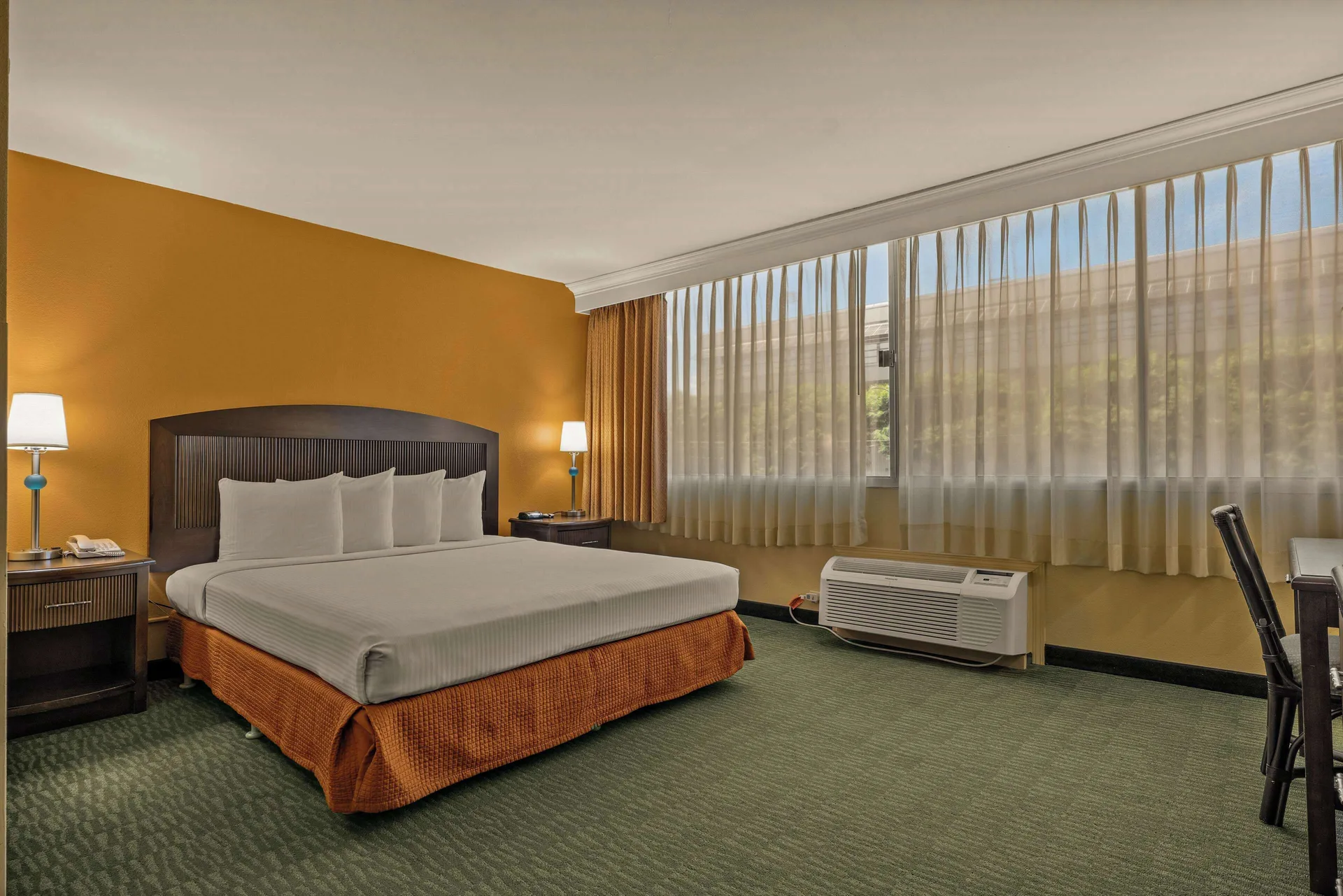 Non-smoking king room with bedside lamps and large window at Airport Honolulu Hotel.
