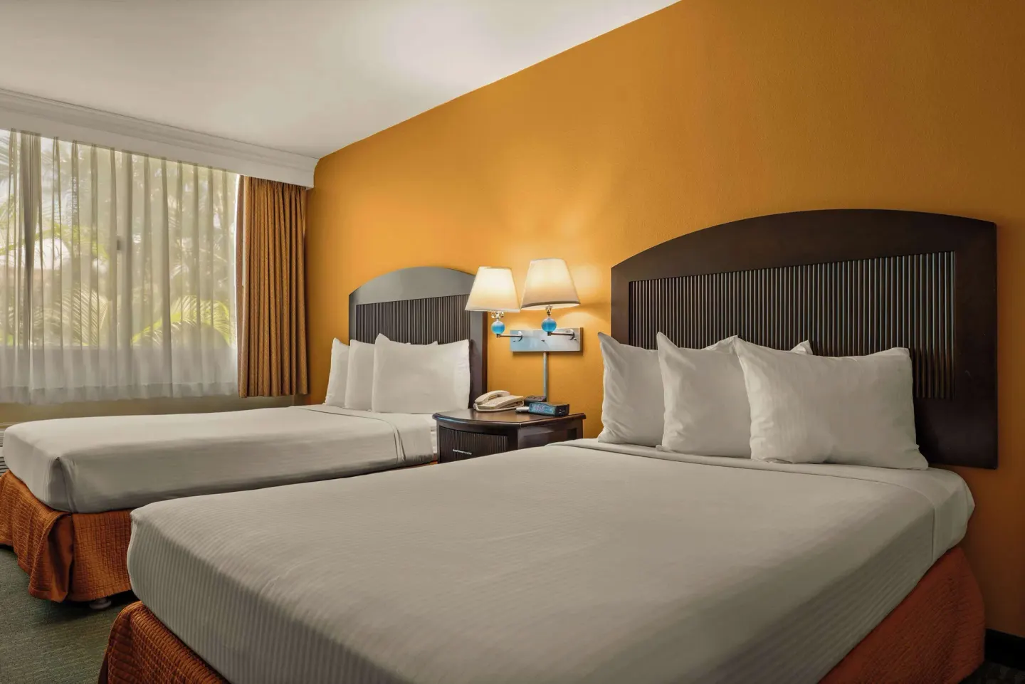 Non-smoking room with two beds, white pillows, and a shared nightstand at Airport Honolulu Hotel.