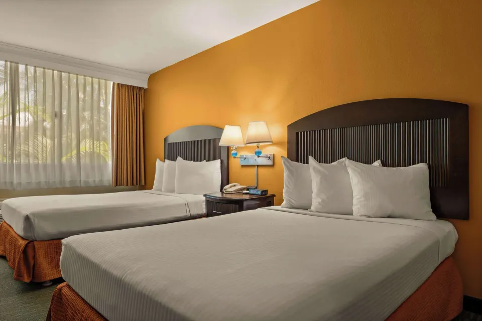 Non-smoking room with two beds, white pillows, and a shared nightstand at Airport Honolulu Hotel.