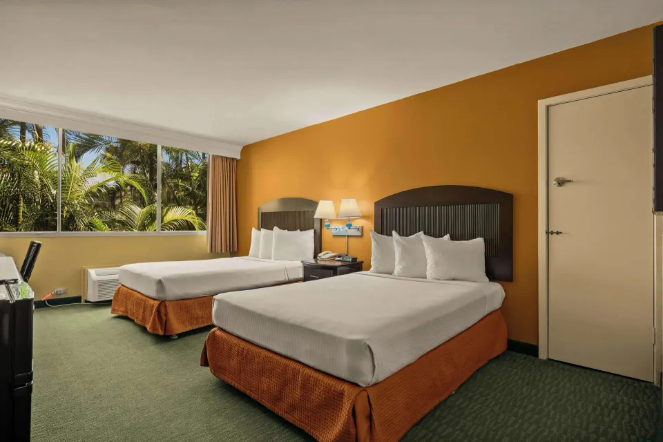 Non-smoking room with two beds, palm-facing window, and air conditioner at Airport Honolulu Hotel.